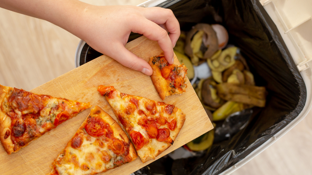 leftover food waste being scraped into a bin